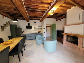 A modern kitchen with a dining area, a fireplace, and a light blue armchair.