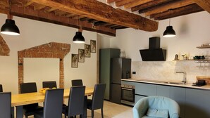 A modern kitchen with a built-in oven, a refrigerator, and a sink. There is a dining area with a wooden table and chairs. - Apartment sleeps 6 located in in the heart  Asciano, with terrace. (Asciano)