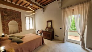 A bedroom with a bed, a desk, a mirror, and a brick wall. - Apartment sleeps 6 located in in the heart  Asciano, with terrace. (Asciano)
