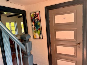 A staircase with a handrail, a door with a brass handle, and a colorful abstract painting on the wall. - 6 Person Holiday Home in Skagen (Skagen)