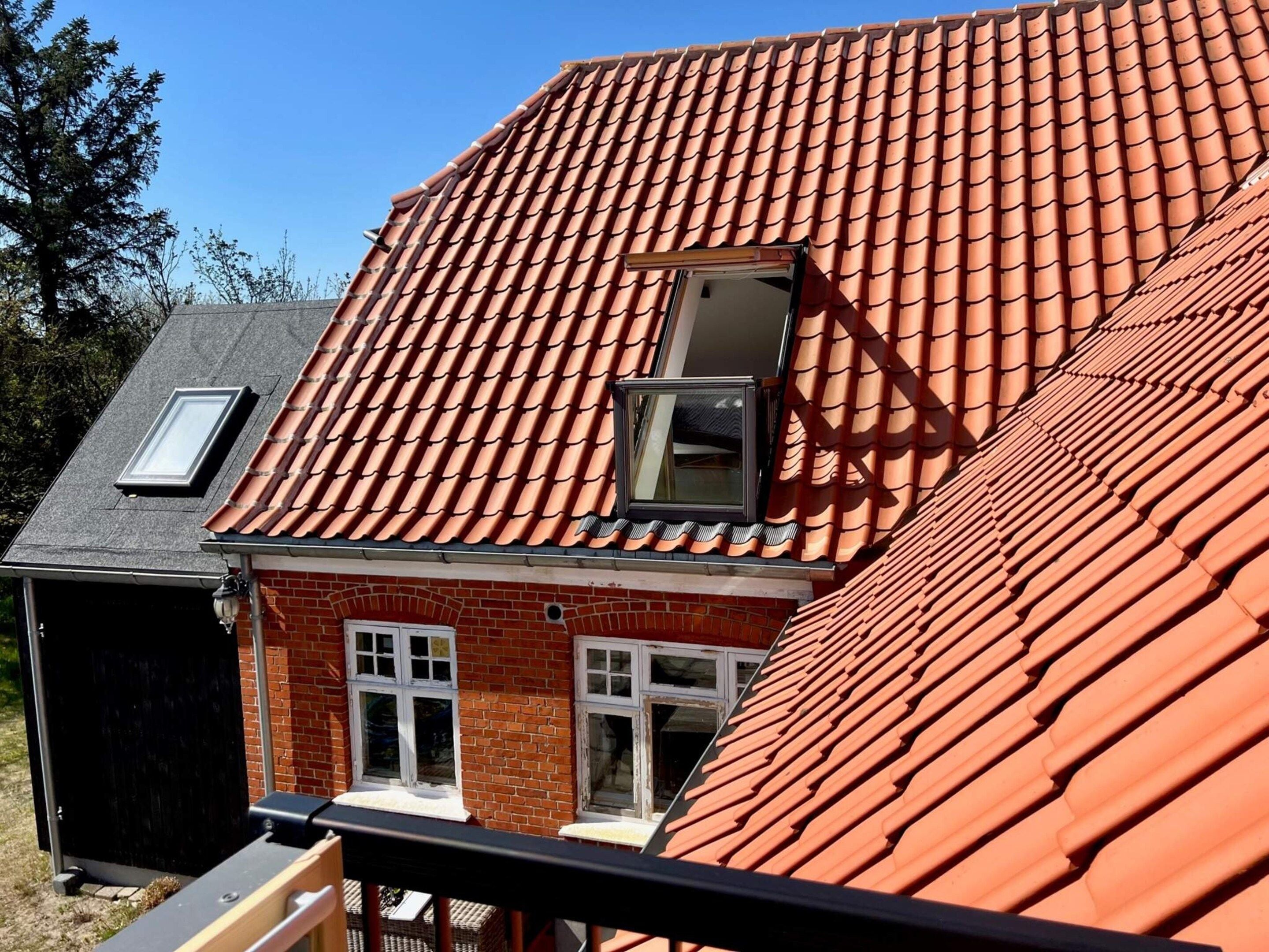 A house with a red-tiled roof, a skylight, and a brick facade.