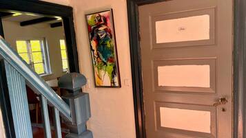 A staircase with a handrail, a door with a brass handle, and a colorful abstract painting on the wall.