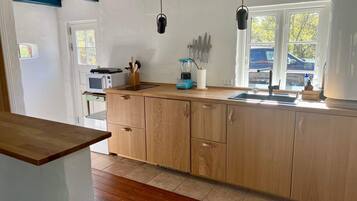 A kitchen with wooden cabinets, a countertop, a sink, a window, and a microwave.