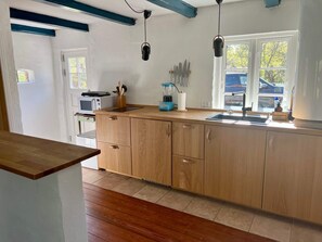 A kitchen with wooden cabinets, a countertop, a sink, a window, and a microwave. - 6 Person Holiday Home in Skagen (Skagen)