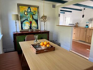 A dining area with a table set for two, a painting above the table, and a kitchen visible through an open doorway. - 6 Person Holiday Home in Skagen (Skagen)