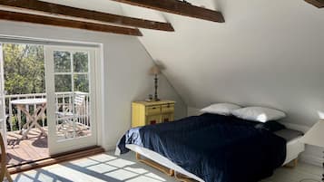 A bedroom with a bed, a nightstand, a lamp, and a view of the outdoors through a sliding door.