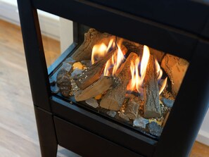 A wood-burning stove with visible flames and logs inside. - Holiday Home Traumstuuv (Varel)