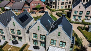 A residential building with a modern design, featuring a mix of brick and stone facades, large windows, and a sloped roof with solar panels. - Holiday Home Traumstuuv (Varel)