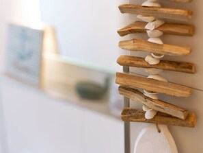 A wall-mounted wooden rack with white pebbles and a white object hanging from it. - Holiday Home Traumstuuv (Varel)