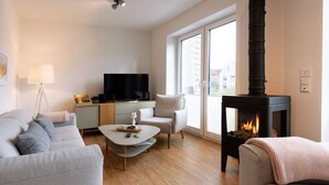 A modern living room with a sofa, a coffee table, a fireplace, and a television. - Holiday Home Traumstuuv (Varel)