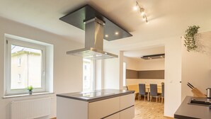 Una cocina moderna con una isla central, un ventanal con vistas y un comedor al fondo.