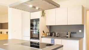 Una cocina moderna con una isla central, horno empotrado y electrodomésticos de acero inoxidable.