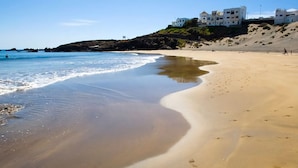 A sandy beach with a clear blue sky and a few buildings in the background. - Belvilla by OYO Holiday Home in Arico El Nuevo (Arico)