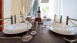 A dining table set with white plates, clear wine glasses, and a bottle of wine. - Belvilla by OYO Holiday Home in Arico El Nuevo (Arico)