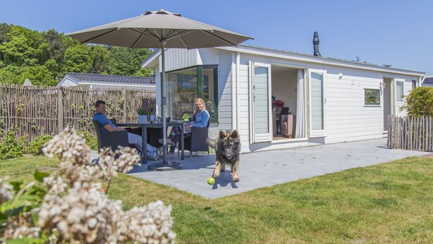 A small house with a patio, a table, and chairs. - Beautiful Chalet Near the sea and Beach (Noordwijk)