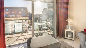 A balcony with a table and chairs, a sofa, a lamp, and a small cabinet. - Apartment in Belgium Near the Sea (Koksijde)