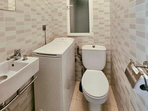 A compact bathroom with a toilet, sink, and washing machine.