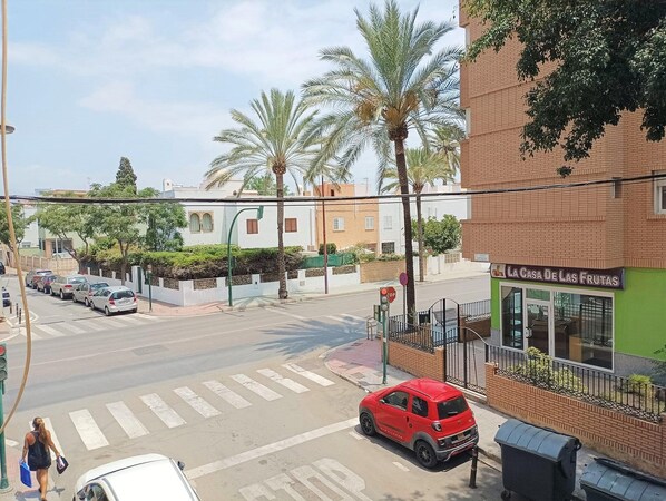 A street view with a red car parked on the side, a pedestrian crossing, and a building with a sign reading "LA CASA DE LAS FRUTAS".