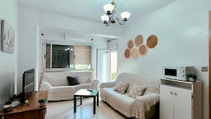 Una sala de estar con un sofá, una mesa de centro, un televisor y un aparador.