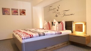 Un dormitorio moderno con cama, mesitas de noche y una pared con texto decorativo.