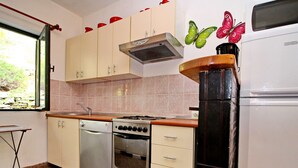 A kitchen with white cabinets, a stove, oven, and a microwave. There are butterfly wall decorations and a window with a view of greenery. - Apartments Sunset - Two Bedroom Apartment With Terrace and Sea View (Blato)