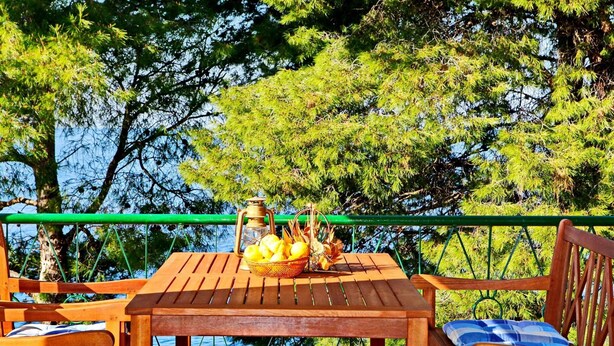 A wooden table with a lantern and a basket of lemons on a terrace with a view of trees and water. - Apartments Sunset - Two Bedroom Apartment With Terrace and Sea View (Blato)