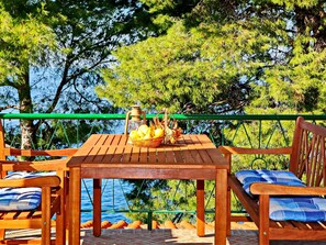 A wooden table with a lantern and a basket of lemons on a terrace with a view of trees and water.