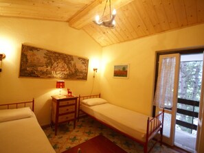 Una habitación pequeña y acogedora con una cama individual, una mesita de noche, una lámpara y un cuadro en la pared.