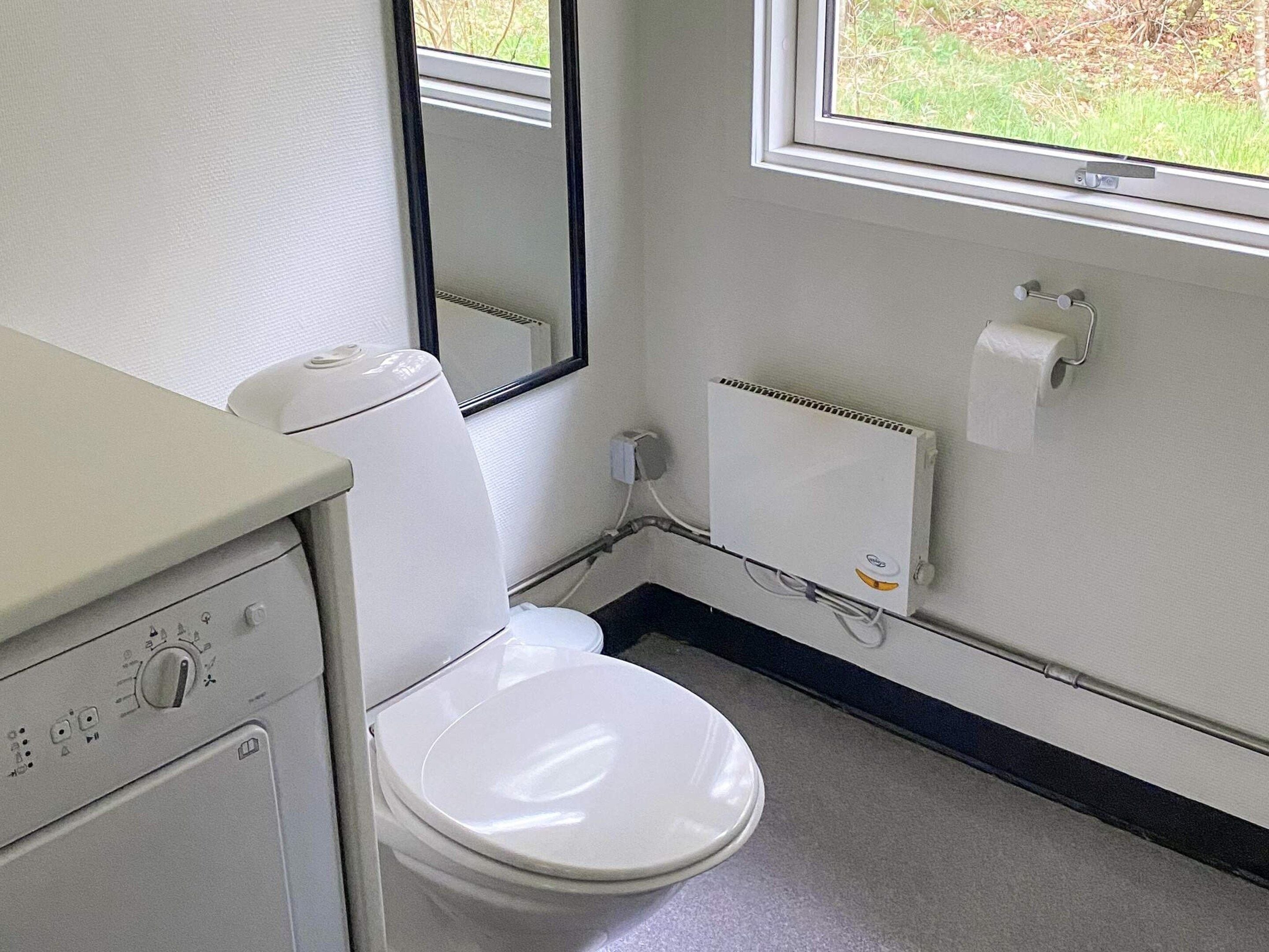 A small, clean bathroom with a toilet, a sink, a mirror, and a window.