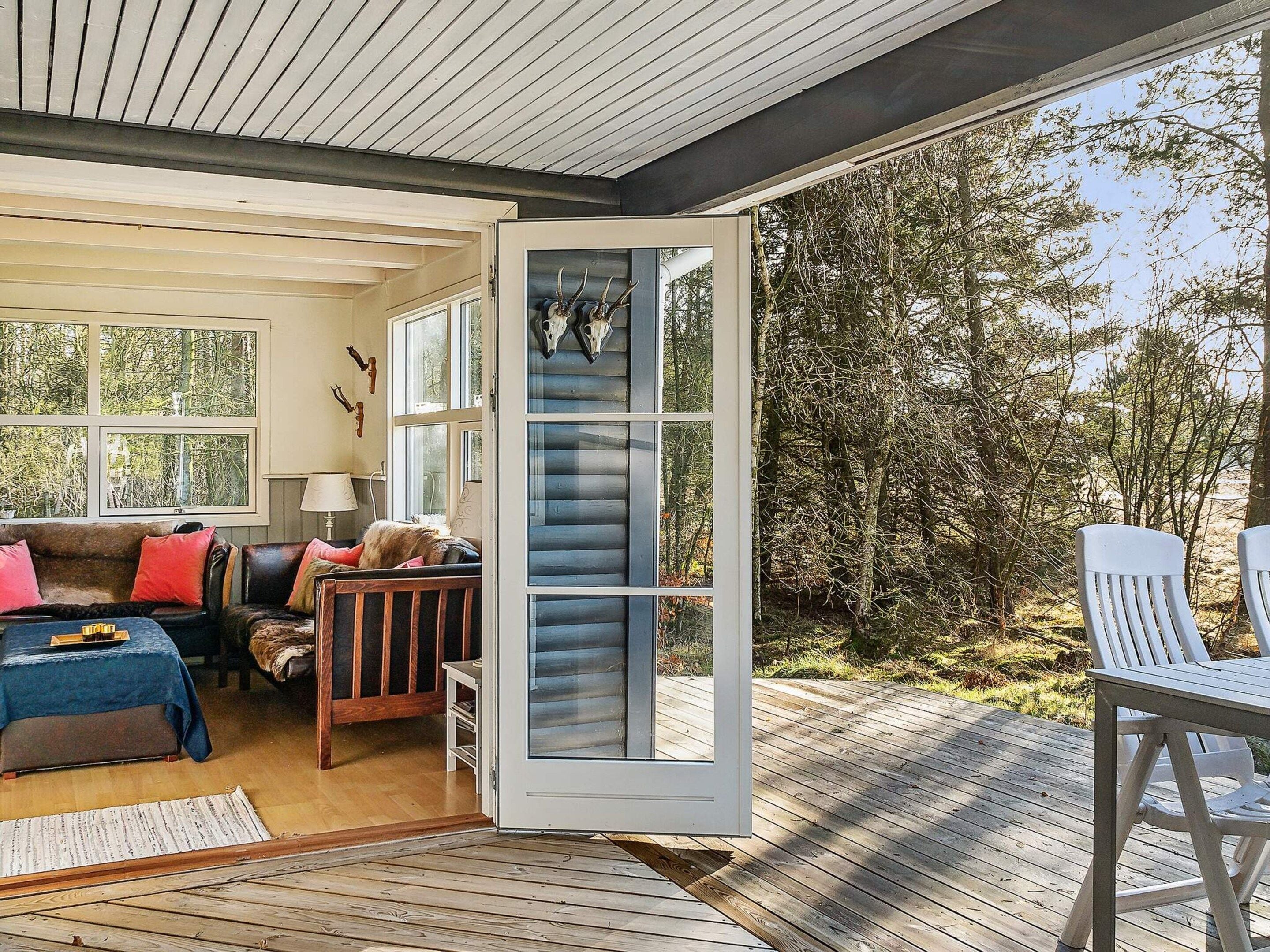 A cozy interior with a wooden deck, a sofa, and a dining area.