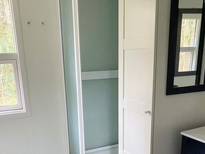 A room with a white door, a window, and a mirror on the wall.