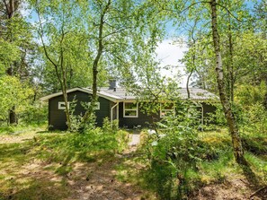A cabin surrounded by dense forest with a clear sky.