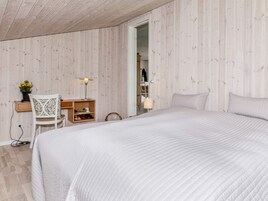 Un dormitorio con una cama grande, un escritorio con silla, una lámpara y un armario.