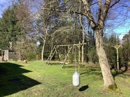 Un conjunto de columpios de madera con una pera colgante en un área verde al aire libre.