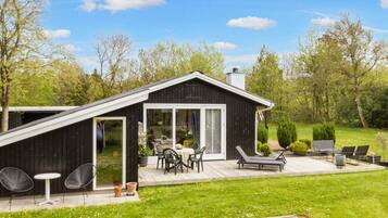 A modern house with a deck, outdoor seating, and a garden.