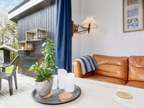 A cozy living area with a brown leather sofa, a table with a tray holding cookies and candles, and a potted plant. - 6 Person Holiday Home in Farso (Farso)