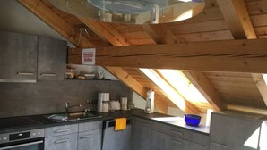 Una cocina moderna con armarios grises, encimera negra y tragaluz.
