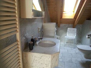 A bathroom with a marble sink, a white chair, and a toilet. - Penthouse in Ostseebad Sierksdorf (Fuessen)