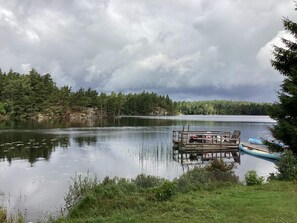 A calm lake with a dock and a small boat, surrounded by dense trees and overcast skies. - 2 Person Holiday Home in Nodinge (Nodinge-Nol)