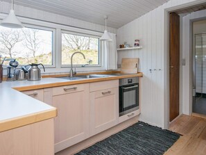 A kitchen with a sink, stove, and wooden cabinets. - 6 Person Holiday Home in Glesborg (Glesborg)
