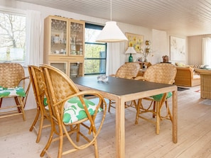 A dining area with wicker chairs and a table, a cabinet with glass doors, and a hanging lamp.