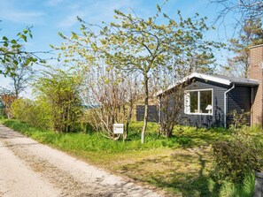 A small house with a visible mailbox, surrounded by trees and a gravel path. - 6 Person Holiday Home in Glesborg (Glesborg)