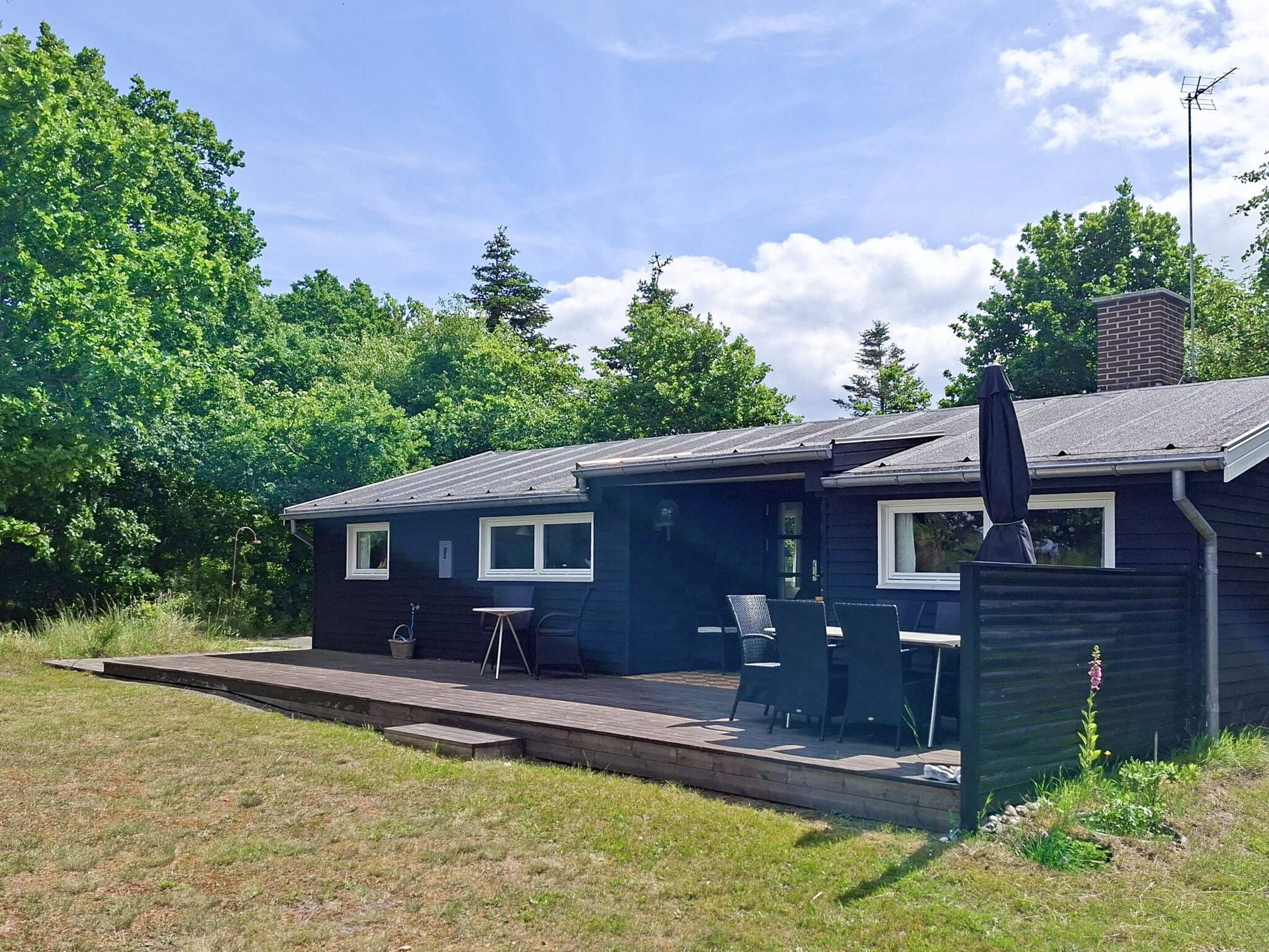 A dark-colored house with a patio, outdoor seating, and a chimney.