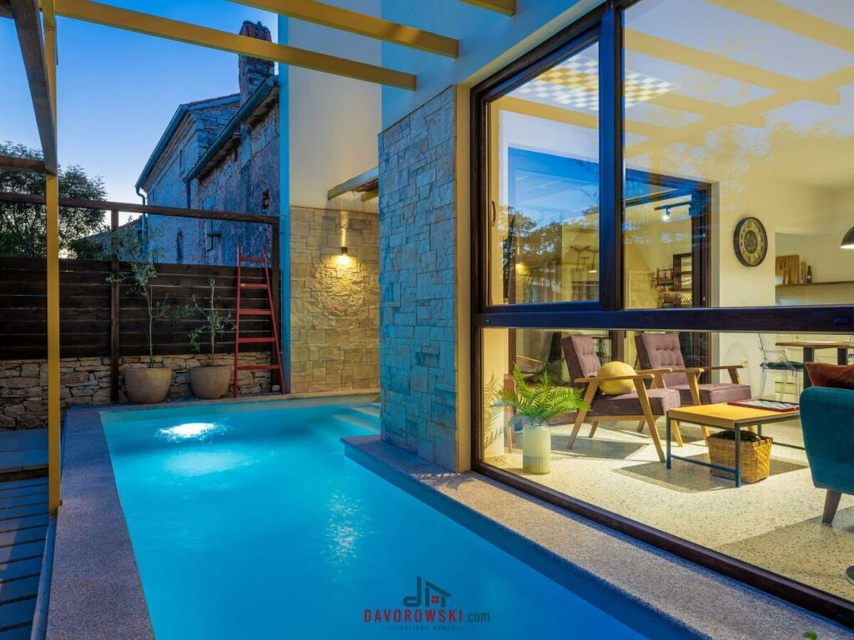 Una casa moderna con piscina, paredes de piedra y ventanas amplias.