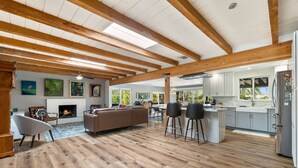 Ein geräumiger Wohnbereich mit Kamin, Holzbalken und einer großen Couch.