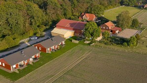 A rural property with multiple buildings, including a large barn and residential houses, surrounded by fields and forested areas. - Siems Modern Retreat (Grube)