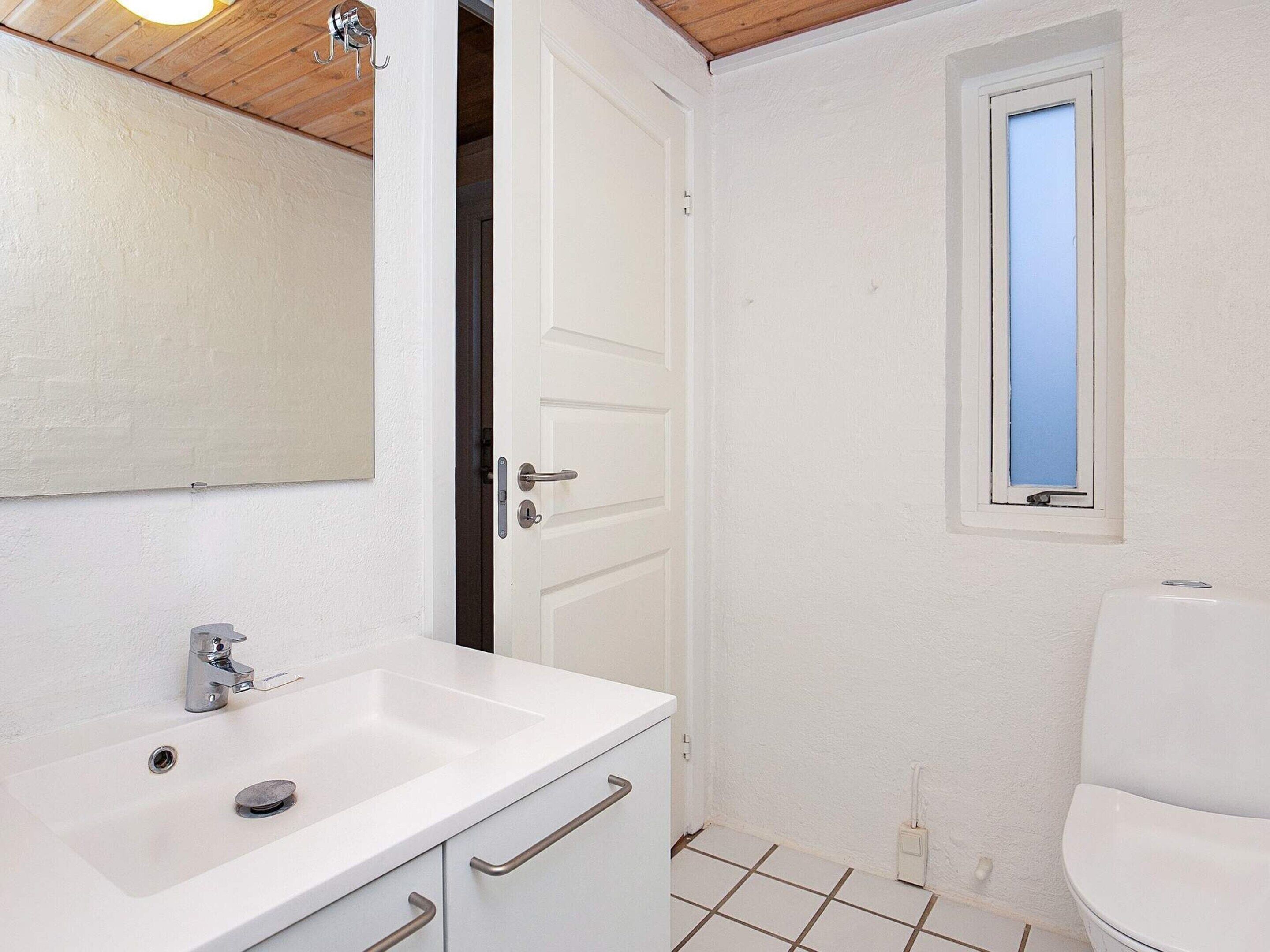 A bathroom with a white sink, mirror, and toilet.