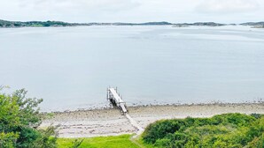 A coastal landscape with a pier extending into calm waters, surrounded by greenery and distant hills. - 4 Star Holiday Home in Ellos (Ellos)