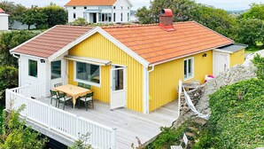 A yellow house with a red roof, a deck, and a chimney. - 4 Star Holiday Home in Ellos (Ellos)
