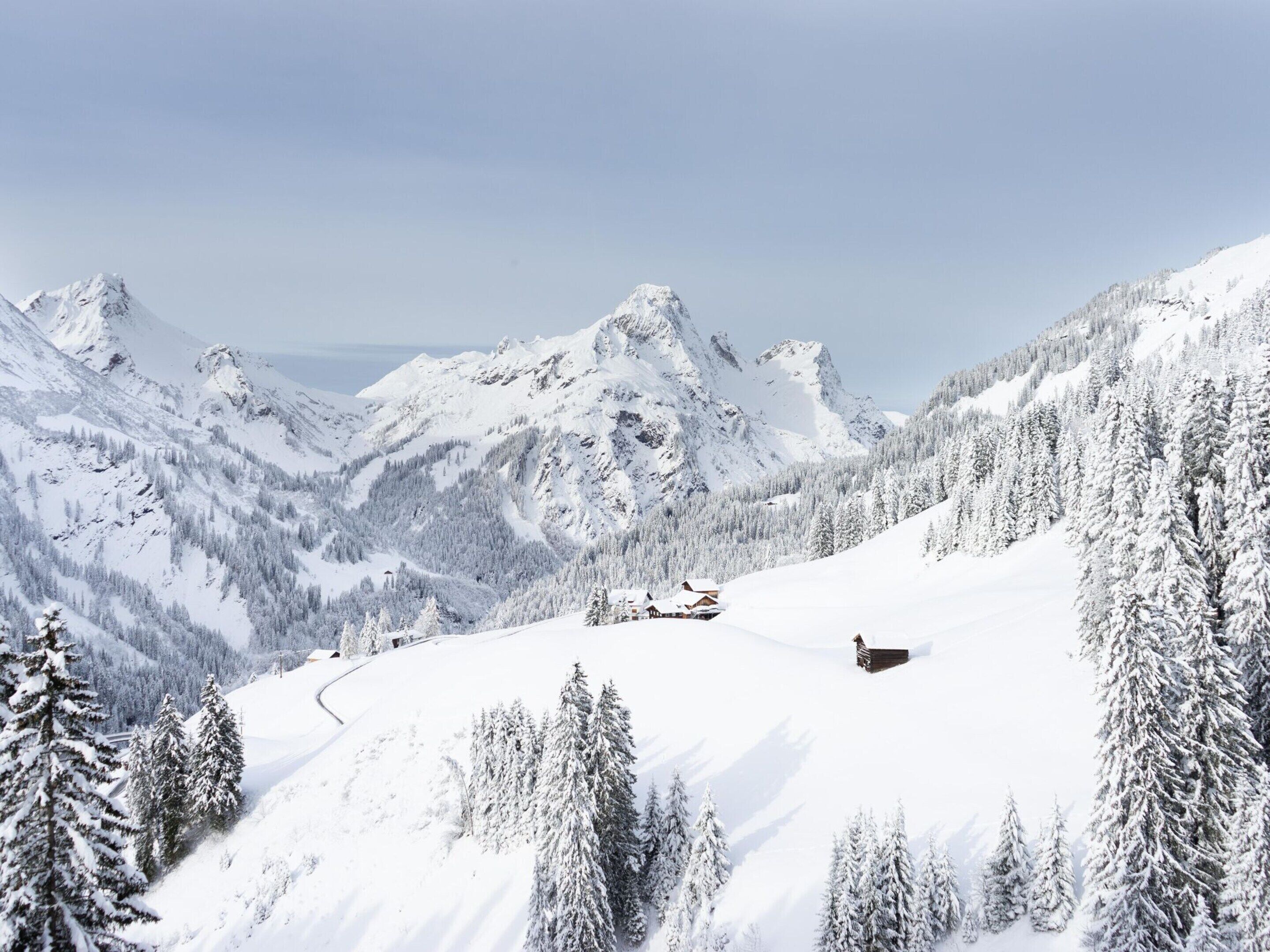 Een berglandschap bedekt met sneeuw, met een chalet en een skilift.